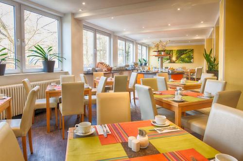 a restaurant with wooden tables and chairs and windows at enjoy hotel Berlin City Messe in Berlin