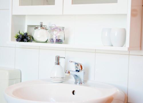 a bathroom sink with a faucet and some cups at Ferienapartments Spreewaldwiesen in Vetschau