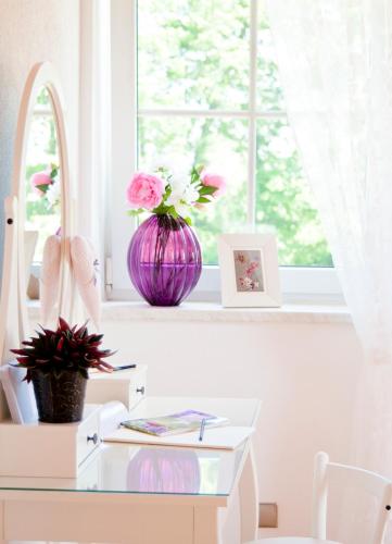 a white table with a vase of flowers in a window at Ferienapartments Spreewaldwiesen in Vetschau