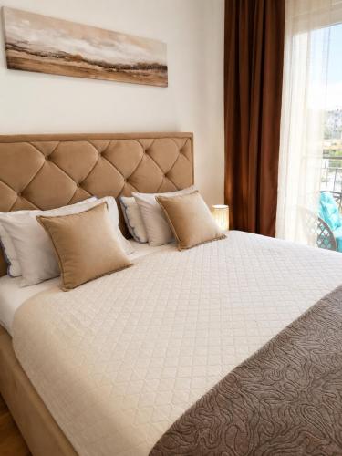 a bedroom with a large bed with pillows and a window at Modern New Apartment Miss T I Free Parking I Great Location in Podgorica