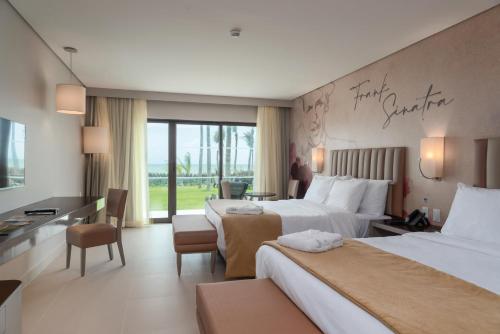 a hotel room with two beds and a desk at Vila Galé Collection Sunset Cumbuco in Cumbuco