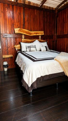 a bedroom with a bed with wooden walls and wooden floors at Xitlaly cabins in La Montaña