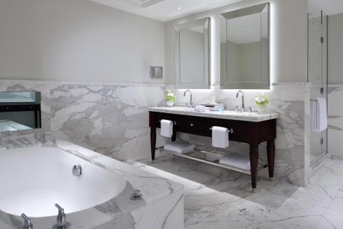 a white bathroom with a tub and a sink at Kempinski The Boulevard Dubai in Dubai