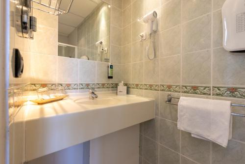 ein Badezimmer mit Waschbecken und Spiegel in der Unterkunft Logis Hôtel Rêve de Sable in Royan