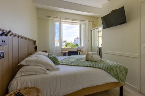 ein Schlafzimmer mit einem Bett und einem Fernseher an der Wand in der Unterkunft Logis Hôtel Rêve de Sable in Royan
