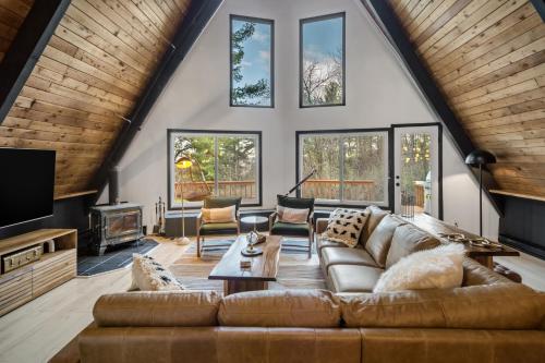 a living room with a couch and a tv at Camp Smores- Modern A-Frame with Pool in Newfield
