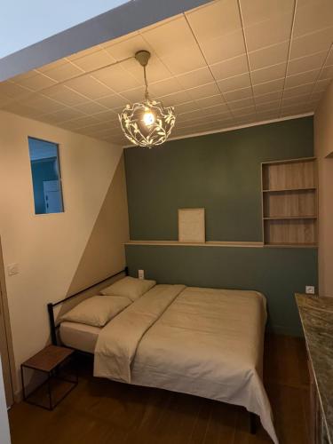 a bedroom with a bed and a chandelier at Le pensionnat de Jeanne in Domrémy-la-Pucelle