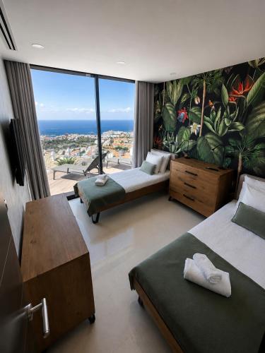 a bedroom with two beds and a large window at Villa de Anna in Adeje