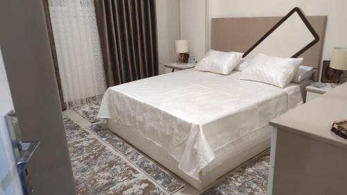 a bedroom with a large white bed with white sheets at Heaven 2 in Mīt Abū Shaykhah
