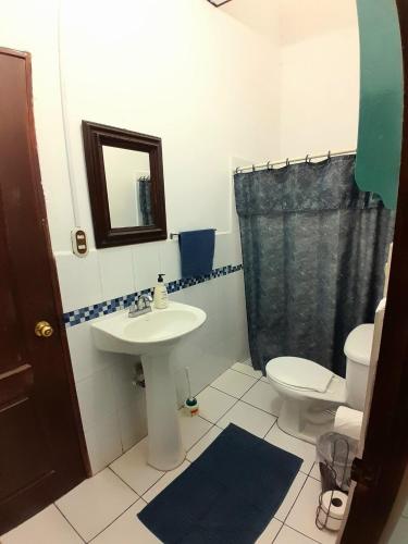 a bathroom with a sink and a toilet and a mirror at GuacamayaGuestHouse in Concepción de Ataco