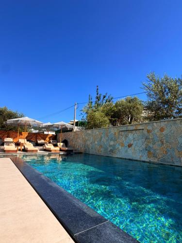 a swimming pool with a stone wall and blue water at Hotel Utopia in Ksamil