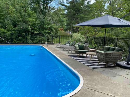 a blue swimming pool with chairs and an umbrella at Camp Smores- Modern A-Frame with Pool in Newfield