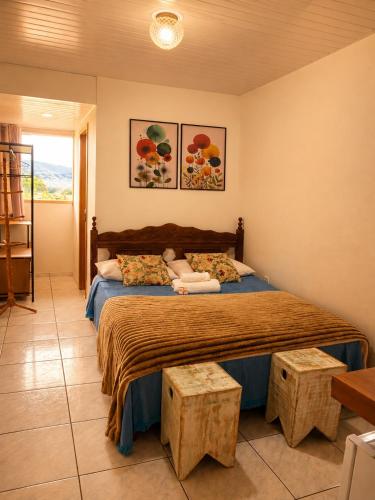 a bedroom with a large bed with two tables at Pertinho do CENTRO - Hospedaria Vila Rica - Excelente Custo Benefício in Ouro Preto