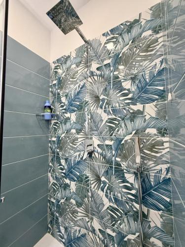 a bathroom with a shower with a green leaf wallpaper at Capri House - camera Luna Caprese in Minori