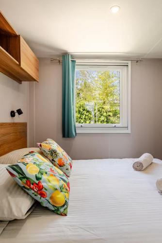 a bedroom with a bed with two pillows and a window at Le petit paradis du golfe in Gassin