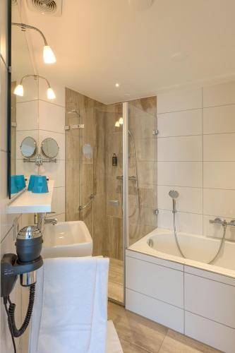 a bathroom with a shower and a sink and a tub at Hotel Op Diek in Den Hoorn