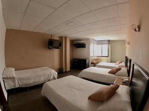 ein Hotelzimmer mit drei Betten und einem Fernseher in der Unterkunft Hotel Italia Cuenca - Tranvia Centro & Aeropuerto in Cuenca