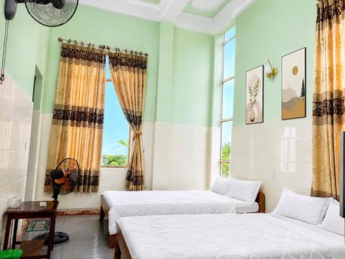 two beds in a room with two windows at ĐAN MY Motel in Dong Hoi