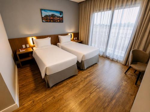 a hotel room with two beds and a window at Royal Tulip Holambra in Holambra