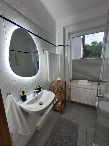 a white bathroom with a sink and a mirror at Ferienwohnung Waldblick in Harrislee