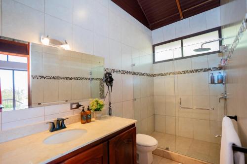 a bathroom with a sink and a toilet and a mirror at Green Forest Rustic Houses in Monteverde Costa Rica