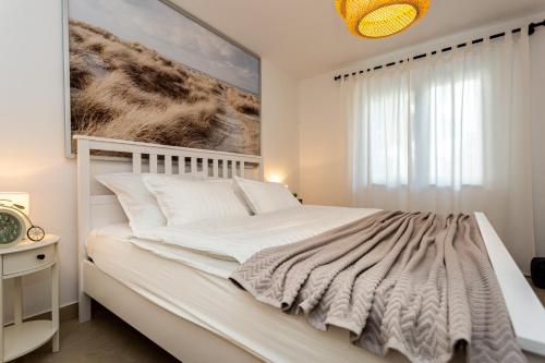 a bedroom with a white bed with a painting on the wall at Apartment Magnolia in Šilo