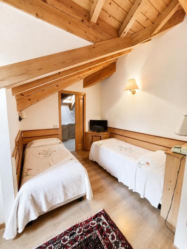 two beds in a room with wooden ceilings at Albergo Al Laghetto B&B in Asiago