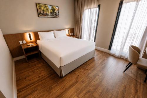 a bedroom with a large white bed and a chair at Royal Tulip Holambra in Holambra