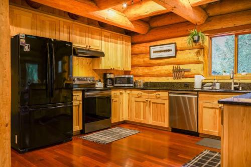 a kitchen with a black refrigerator and wooden cabinets at Wilderness Retreat in Glacier