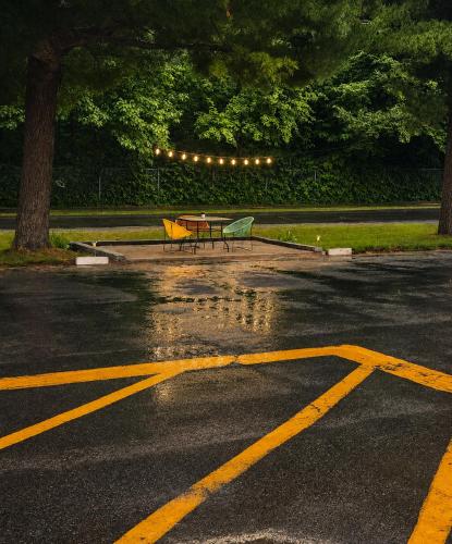 a table and benches in a parking lot in the rain at Motel Bonsoir in Joliette