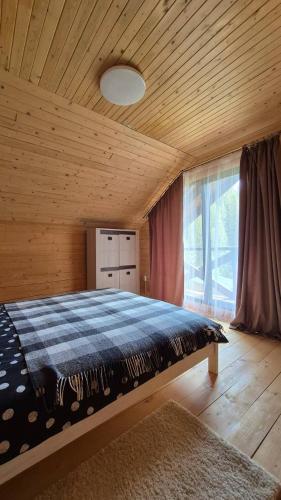 a bedroom with a bed and a large window at Forest House in Yablunytsya