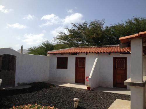 a white house with brown doors and a fence at Villa Morabeza Guest House in Mindelo
