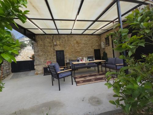 a patio with a table and chairs and a stone wall at Eagles Nest Guesthouse- Garden Lily House in Batroûn