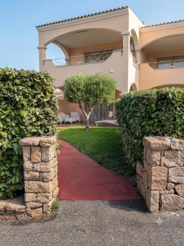 a house with a red sidewalk in front of a building at Suite con giardino in La Maddalena