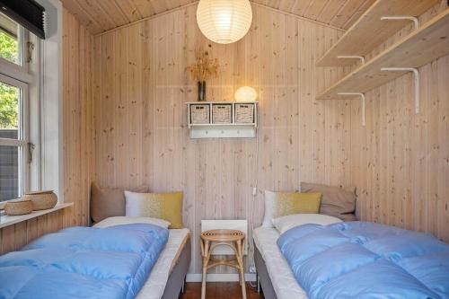 two beds in a room with wooden walls at 1195-Ringkobing-Risbjergvej-84 in Ringkøbing