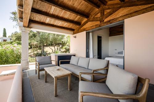 a patio with a couch and chairs and a bed at BeLocations - Aldia Garden Seaview in Puntaldia