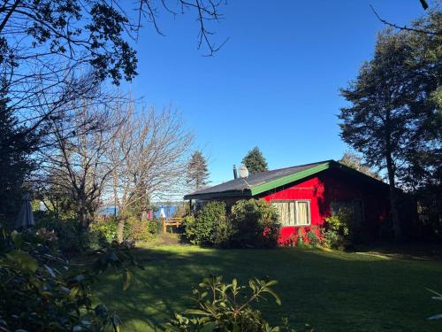 a red barn sitting in the middle of a yard at cabañas kiel in Llanquihue