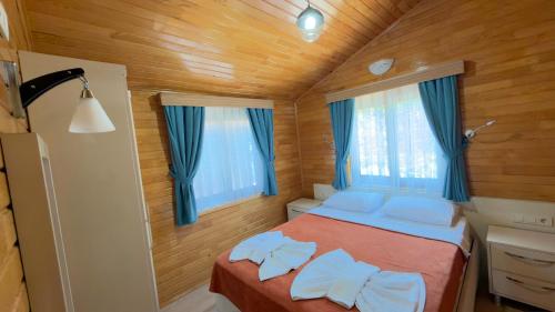 a small bedroom with a bed with blue curtains at Villa Efsane Hotel in Cıralı