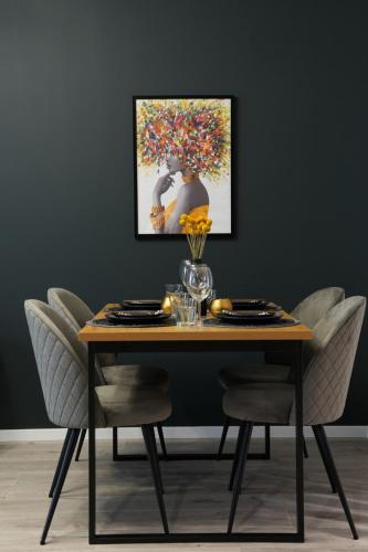 a dining room table with a painting on the wall at Luca - Luxury Park-View Apt with Balcony in Bucharest