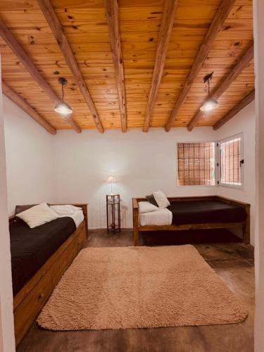 two beds in a room with wooden ceilings and a rug at Apartamento Cerrito in San Rafael