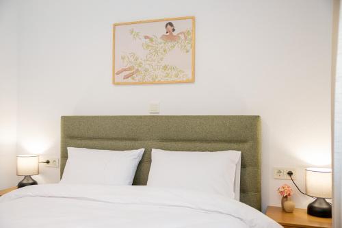 a bed with white sheets and a picture above it at Green Almond's Comfort Apartment in Orfánion