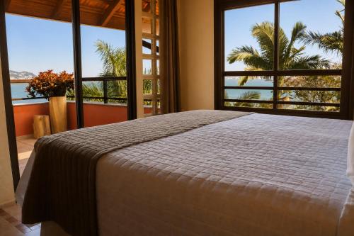a bedroom with a bed and large windows at Refúgio do Cacupé in Florianópolis