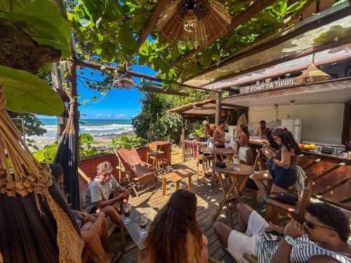 a group of people sitting in chairs on a patio with the beach at Pousada Tiririca Surf in Itacaré