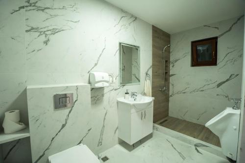 a white bathroom with a sink and a mirror at Vila Popasul Dacilor in Grădiştea de Munte