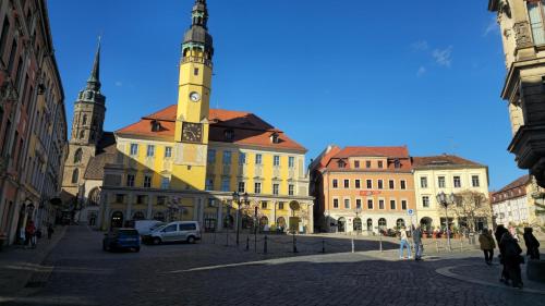 a yellow building with a clock tower on a street at Ferienwohnungen auf einem rustikalen 3 Seitenhof in Göda