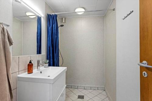 a bathroom with a white sink and a blue shower curtain at LL275-svendborg-Stenklovervej-2 in Svendborg