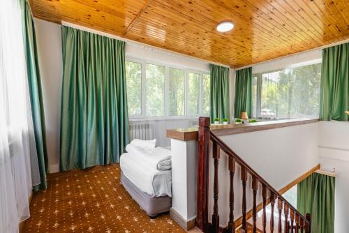 a bedroom with green curtains and a bed in a room at Tau Shyraq in Almaty