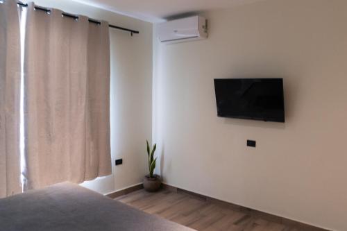 a bedroom with a flat screen tv on a white wall at Hotel Casa Arbórea in San José