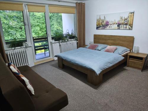 a bedroom with a bed and a couch and windows at Apartmán Jarka in Bodice
