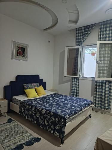 a bedroom with a bed with yellow pillows and a window at maison entre forêt et mer in Raʼs al Jabal